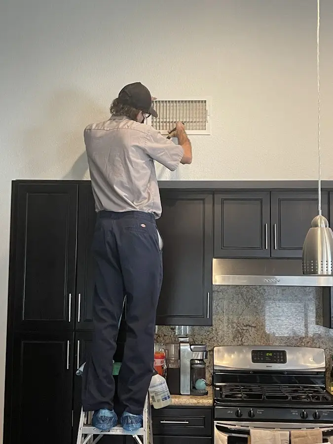 Technician inspecting an air vent during HVAC service in Boone